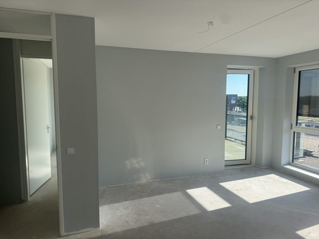 Lichte kamer met een glad gesausde wand waar renovlies behang op zit